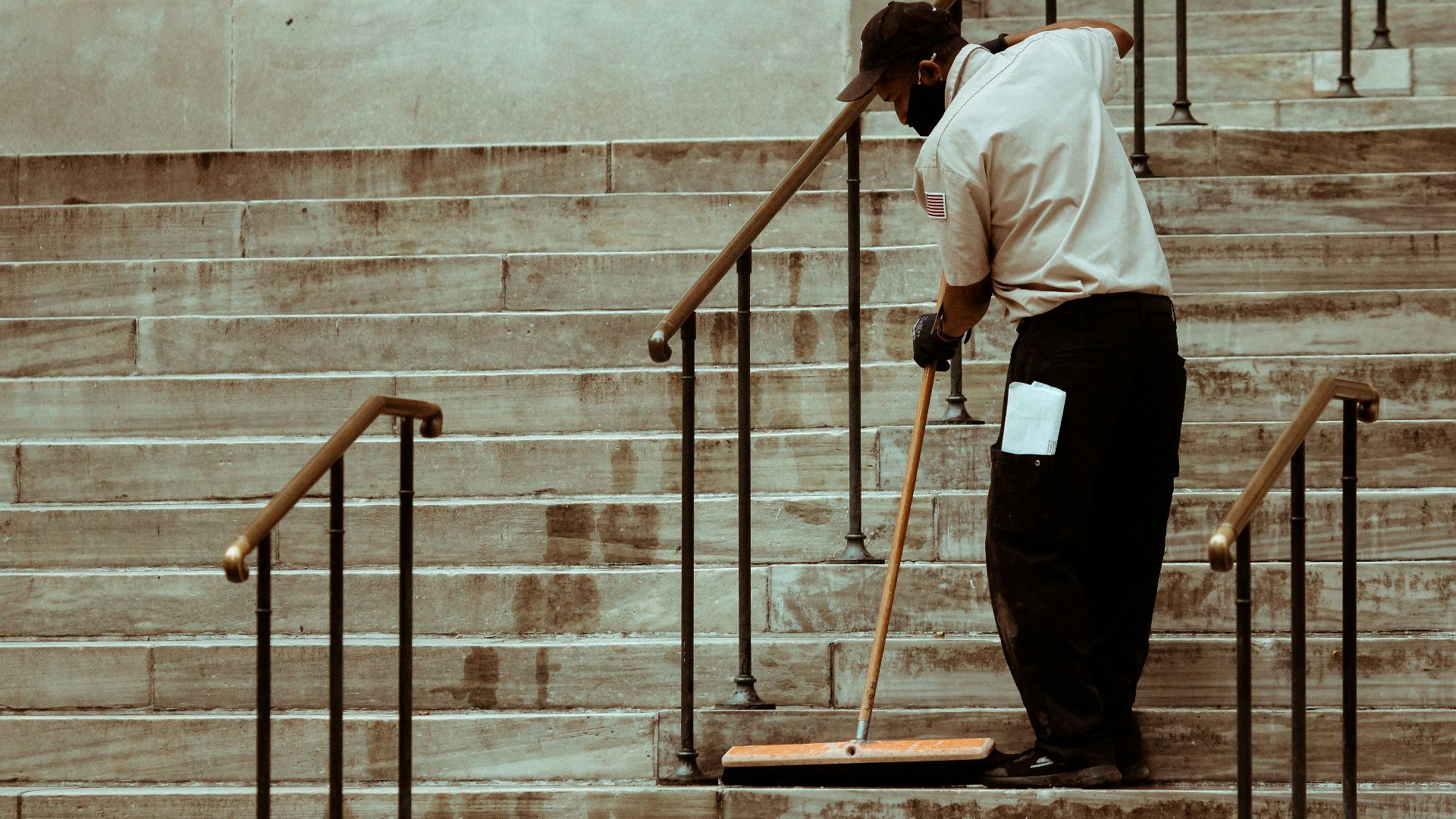 man in white dress shirt and black pants standing on brown wooden ladder