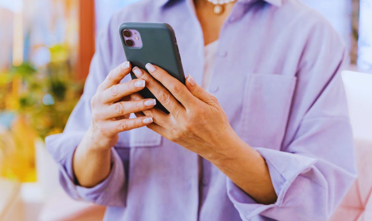 A close-up of an adult using a smartphone indoors, showcasing modern technology