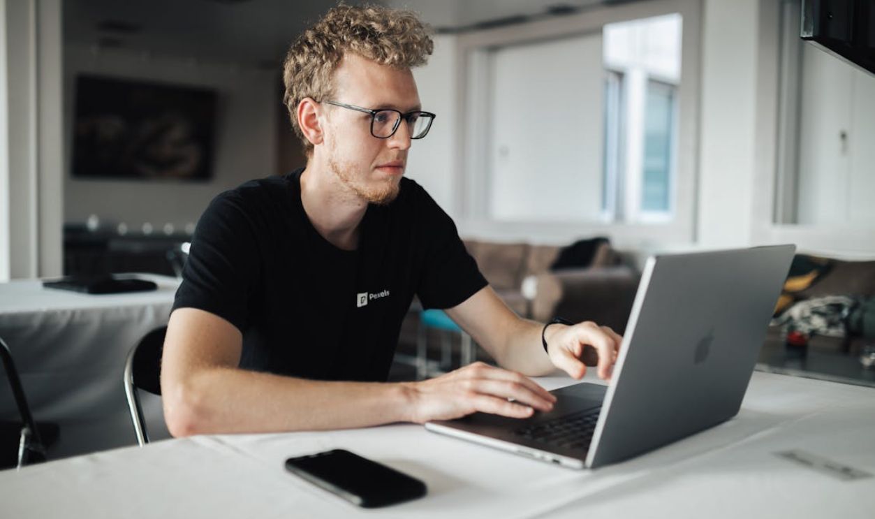 A focused young man working on a laptop in a modern office setting, highlighting productivity and technology.
