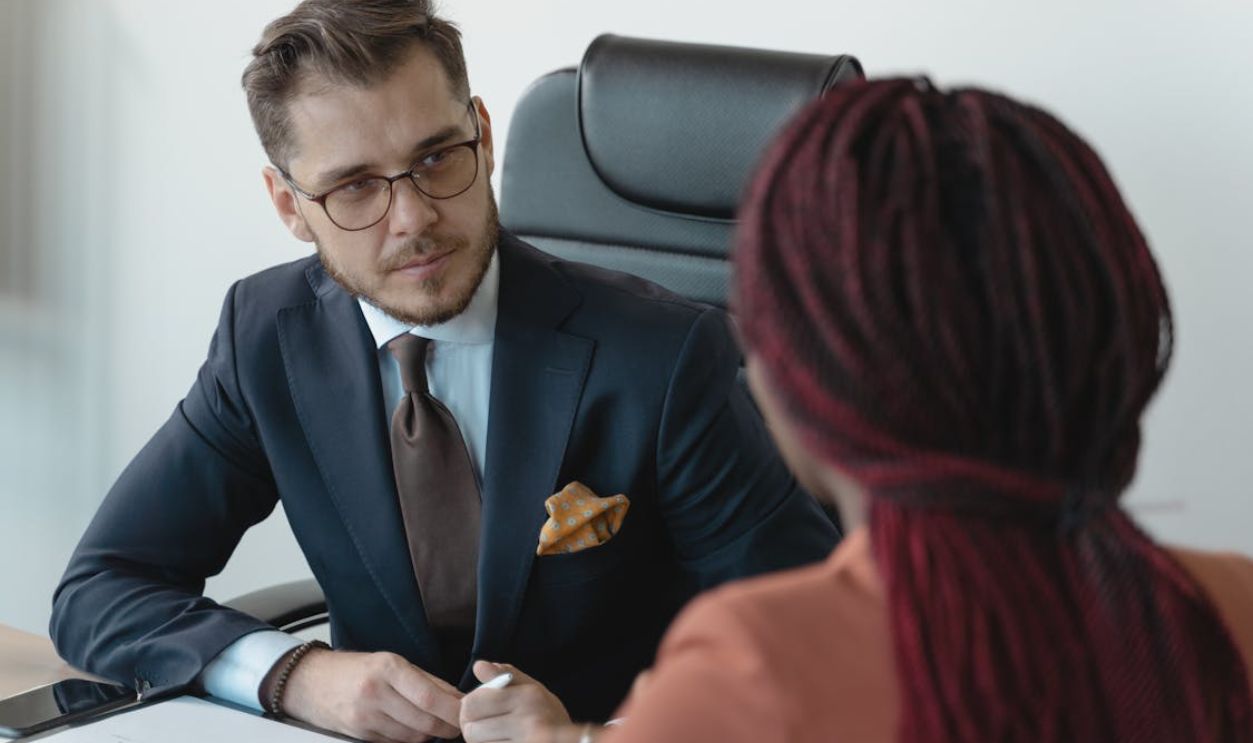 Two professionals engage in a serious discussion at a corporate meeting.
