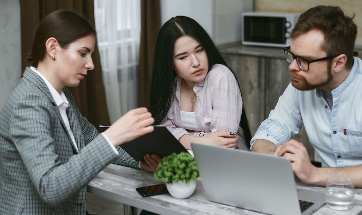 Three colleagues discussing a project together with a laptop in an office environment.