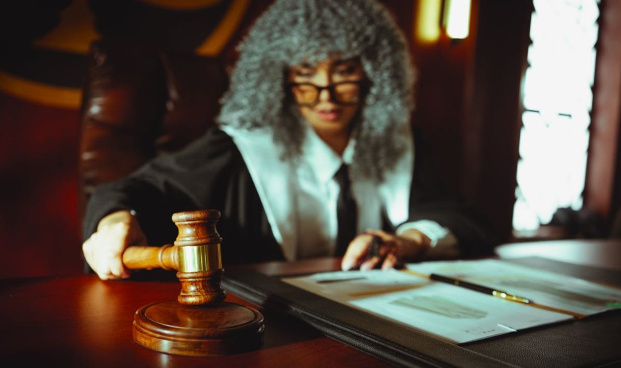 Female judge in a courtroom setting, focusing on legal documents with a gavel.