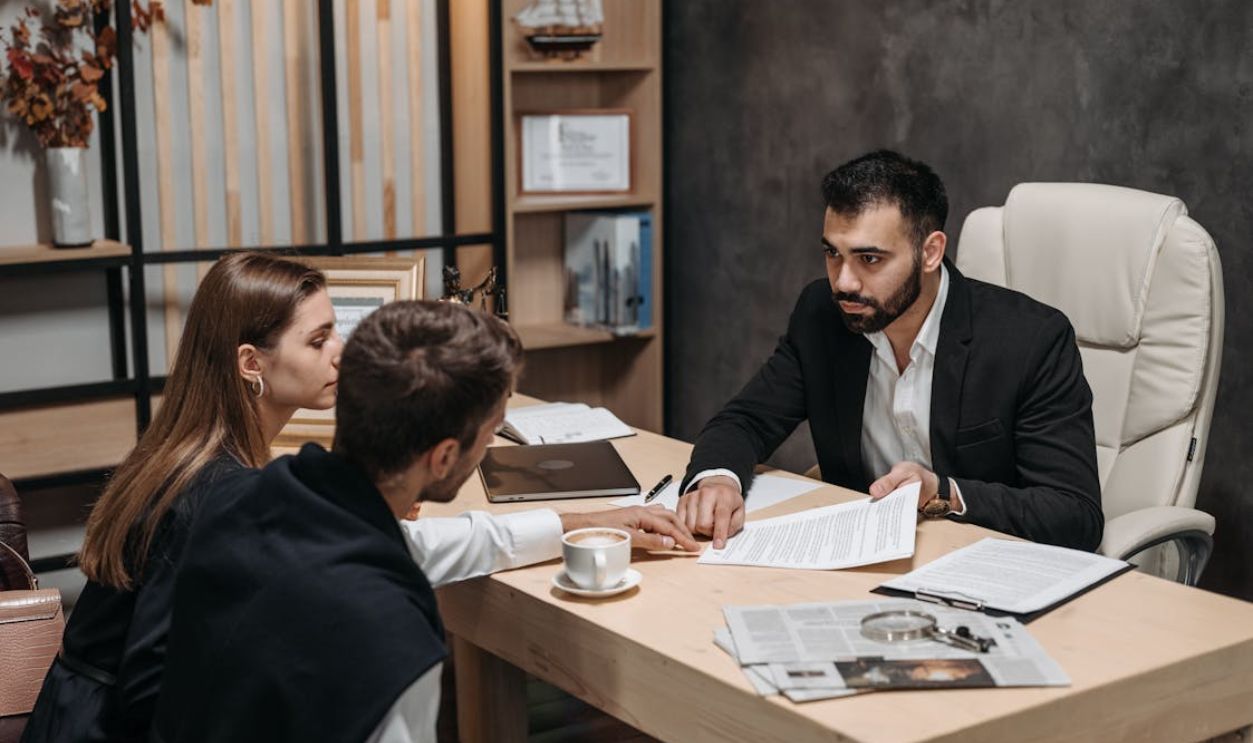 Lawyer discussing legal documents with clients at office desk.