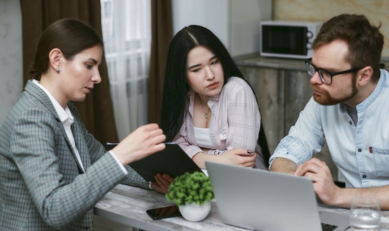 Three colleagues discussing a project together with a laptop in an office environment.
