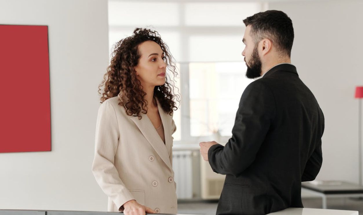 Two professionals engaged in a discussion in a bright, modern office setting.