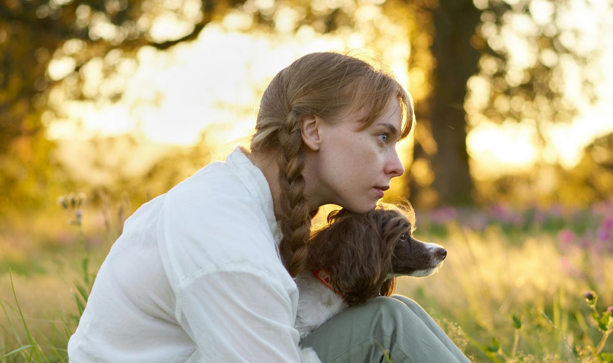 Serene moment of a woman with her dog in a sunlit meadow, capturing peaceful companionship