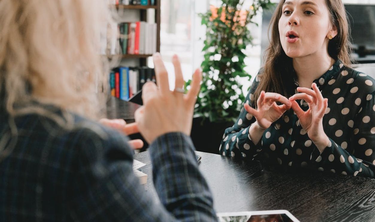 Two women communicating using sign language in a library