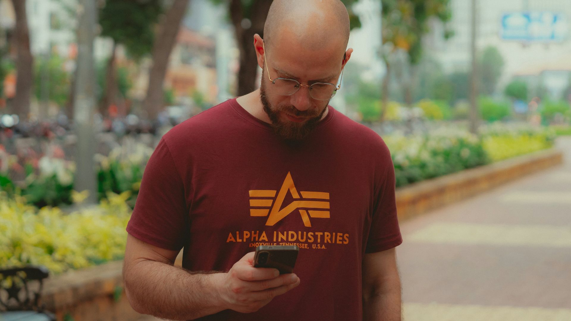 A man standing on a sidewalk looking at his cell phone