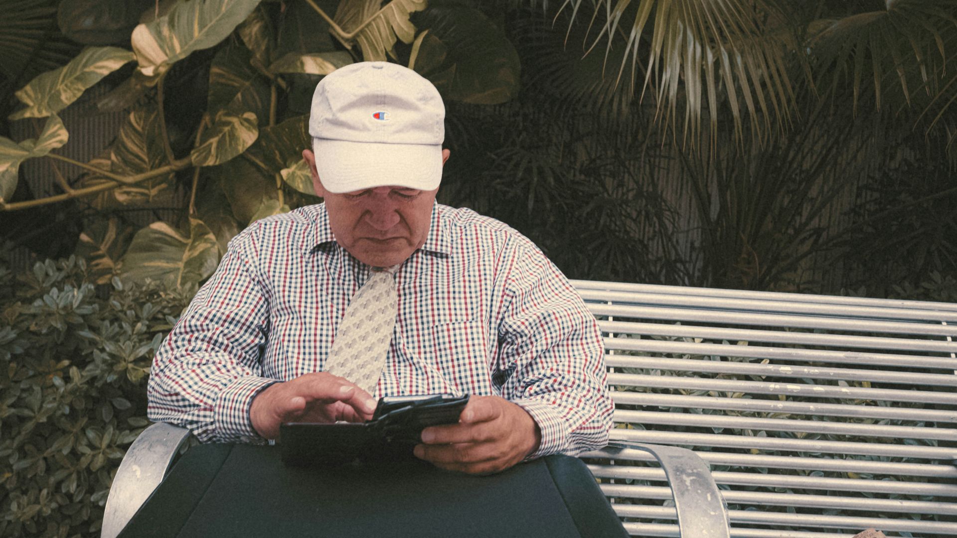 a man sitting on a bench looking at his cell phone