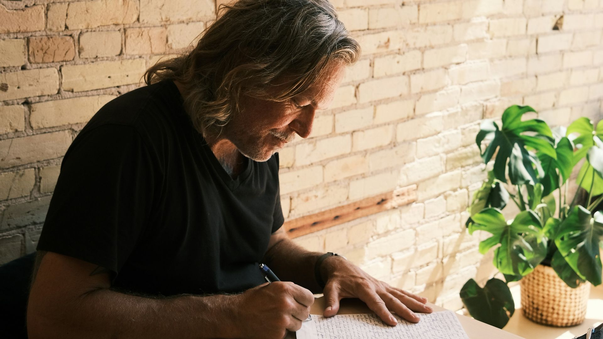 a man sitting at a table writing on a notebook