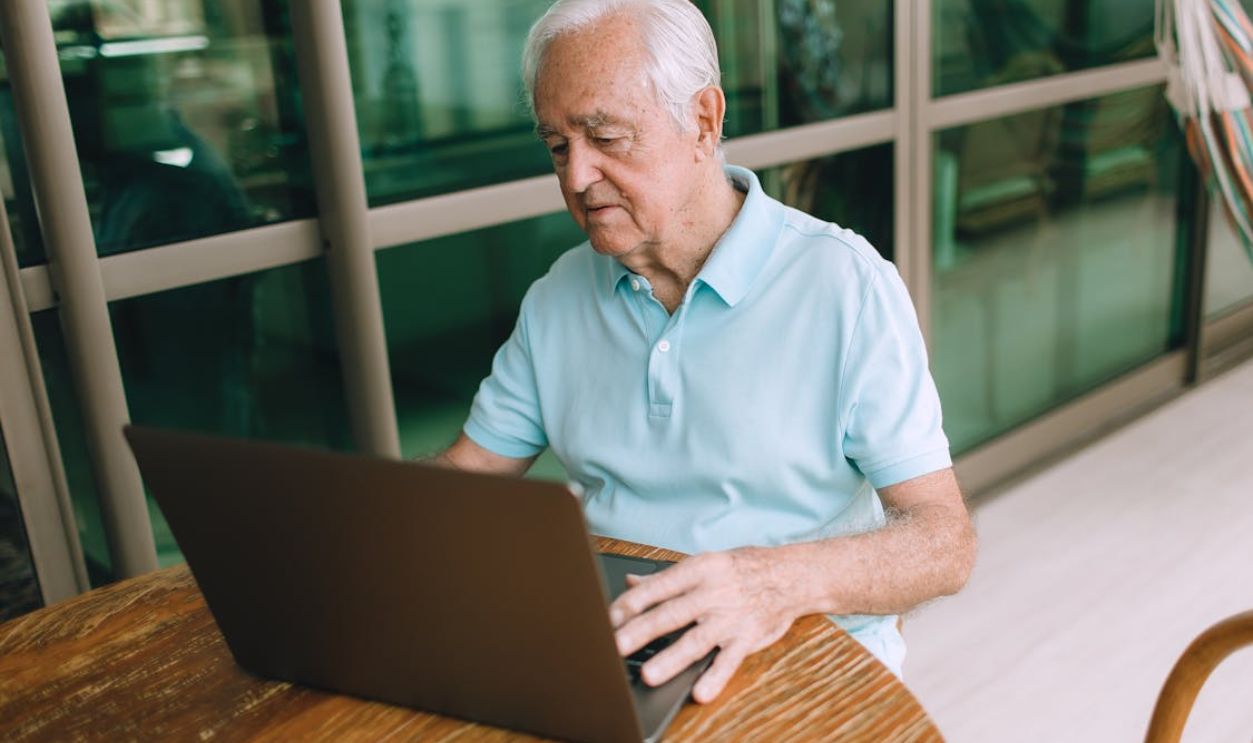 An elderly man focused on using a laptop indoors, highlighting technology and connectivity