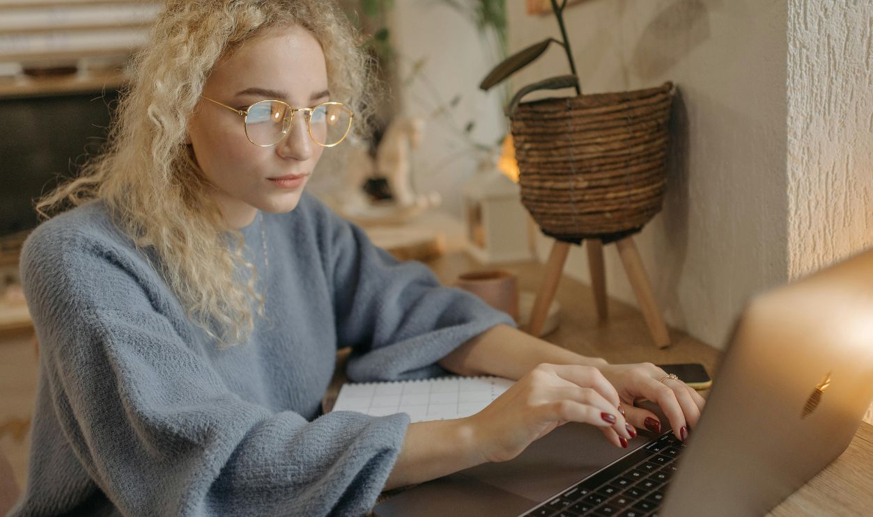 Focused young woman with curly hair working on her laptop in a cozy home office setting