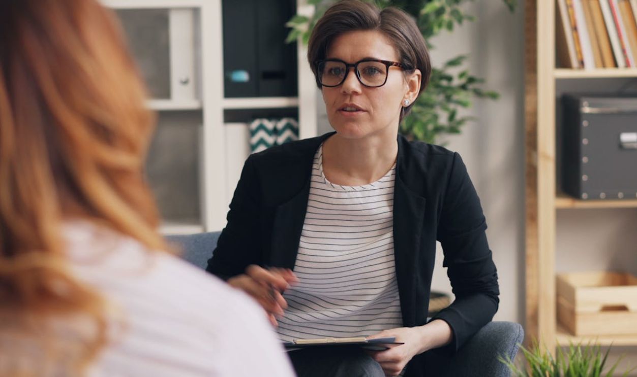 A professional therapist in a modern office setting engaged in a discussion with a client