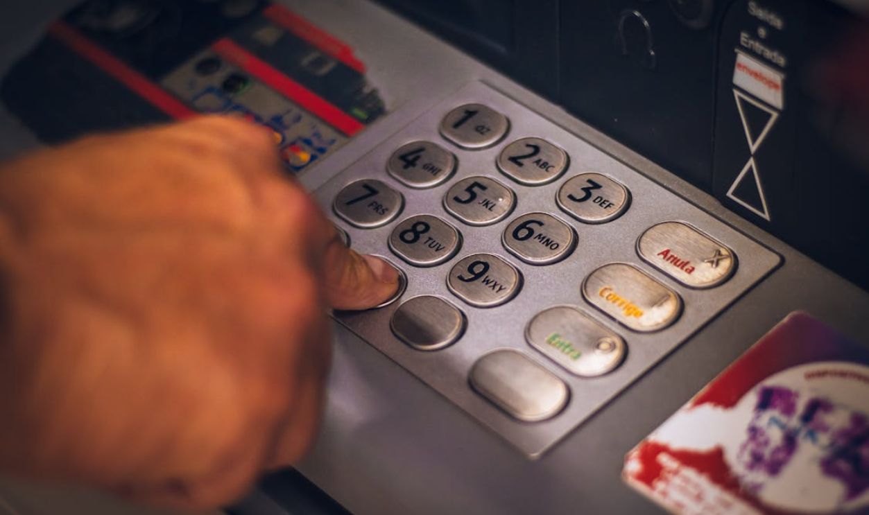 A hand pressing a button on an ATM keypad in Brasil, emphasizing digital banking