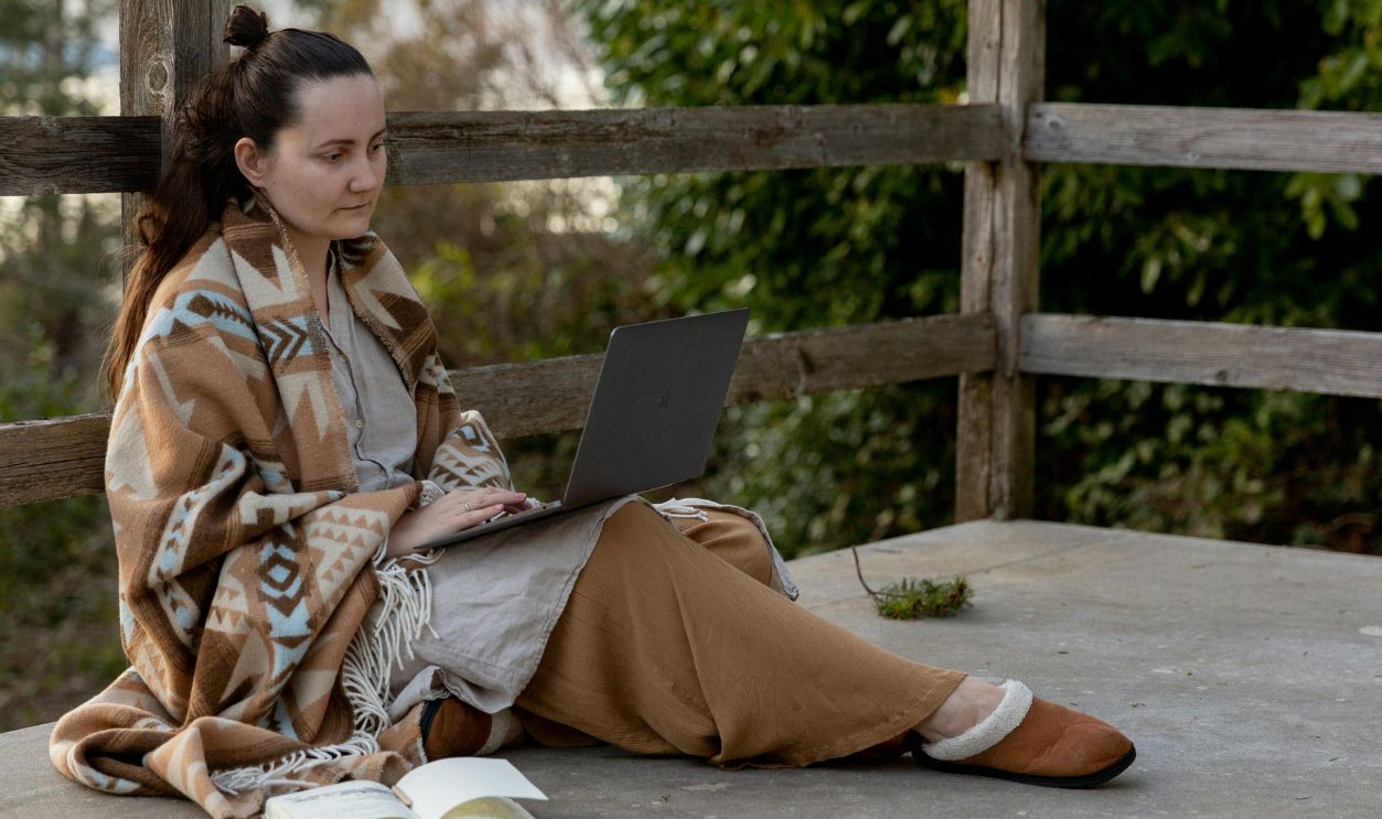 A woman working on a laptop outdoors on a terrace, enjoying a peaceful moment