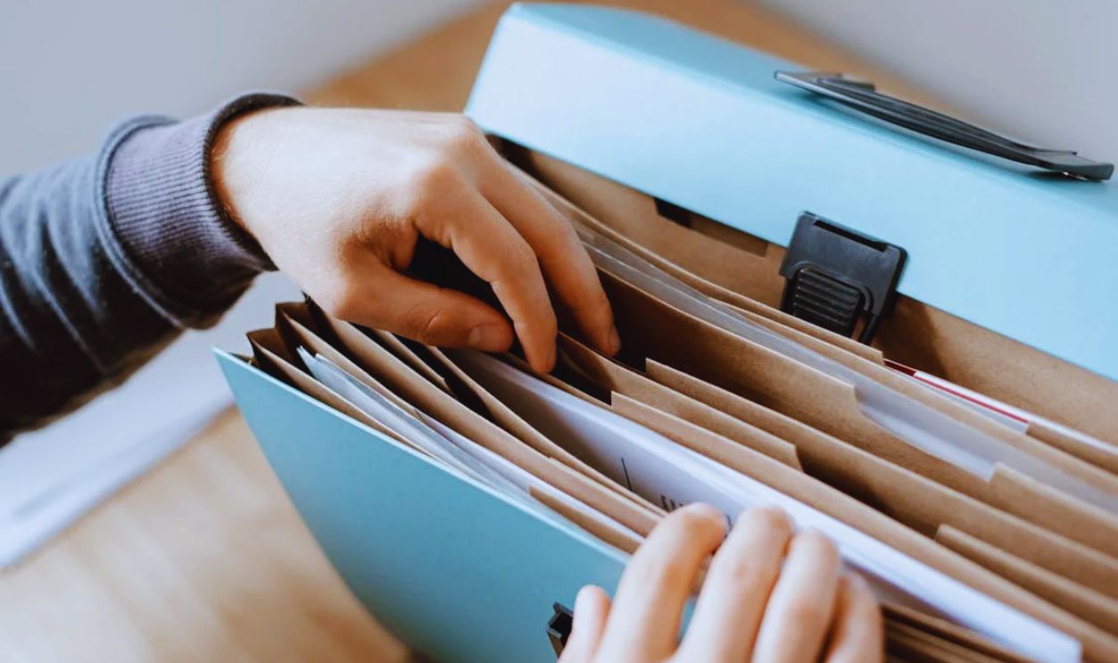 Close-up of hands organizing papers in a blue folder, ideal for business and office concepts