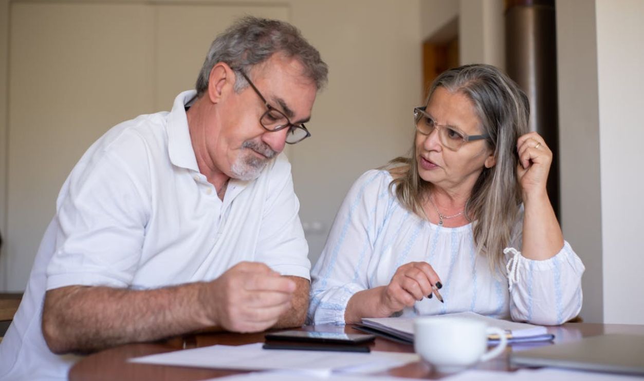 Senior couple reviewing documents and managing finances together at home, showing collaboration and care.