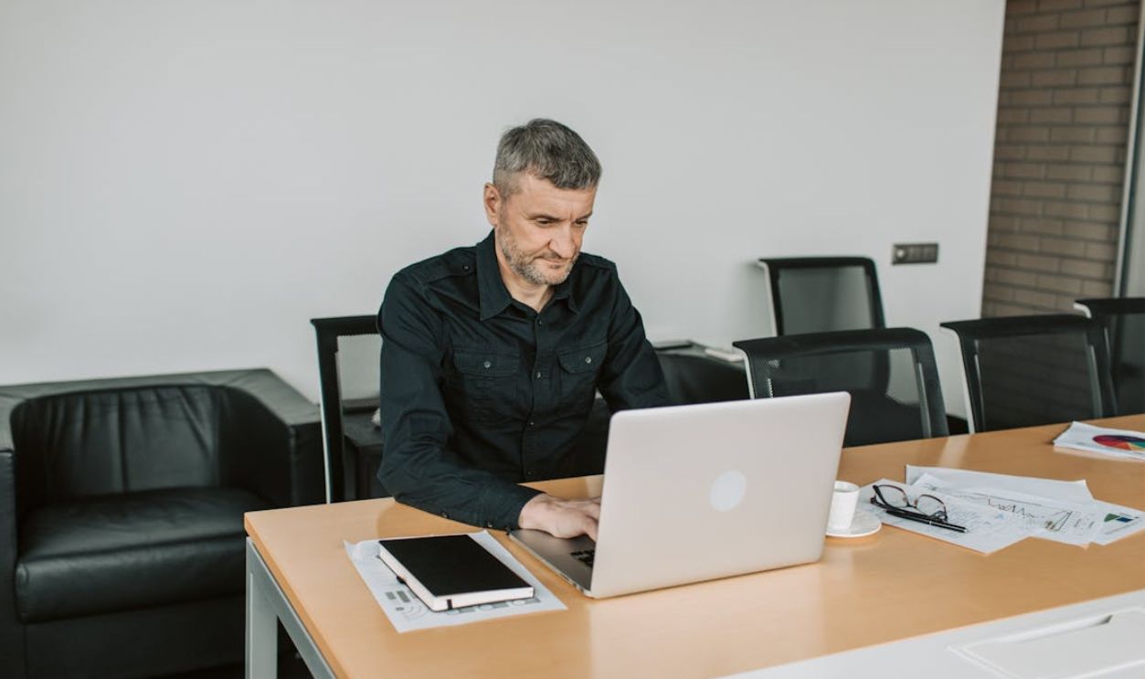 Mature man focusing on his laptop while working in a modern office environment.