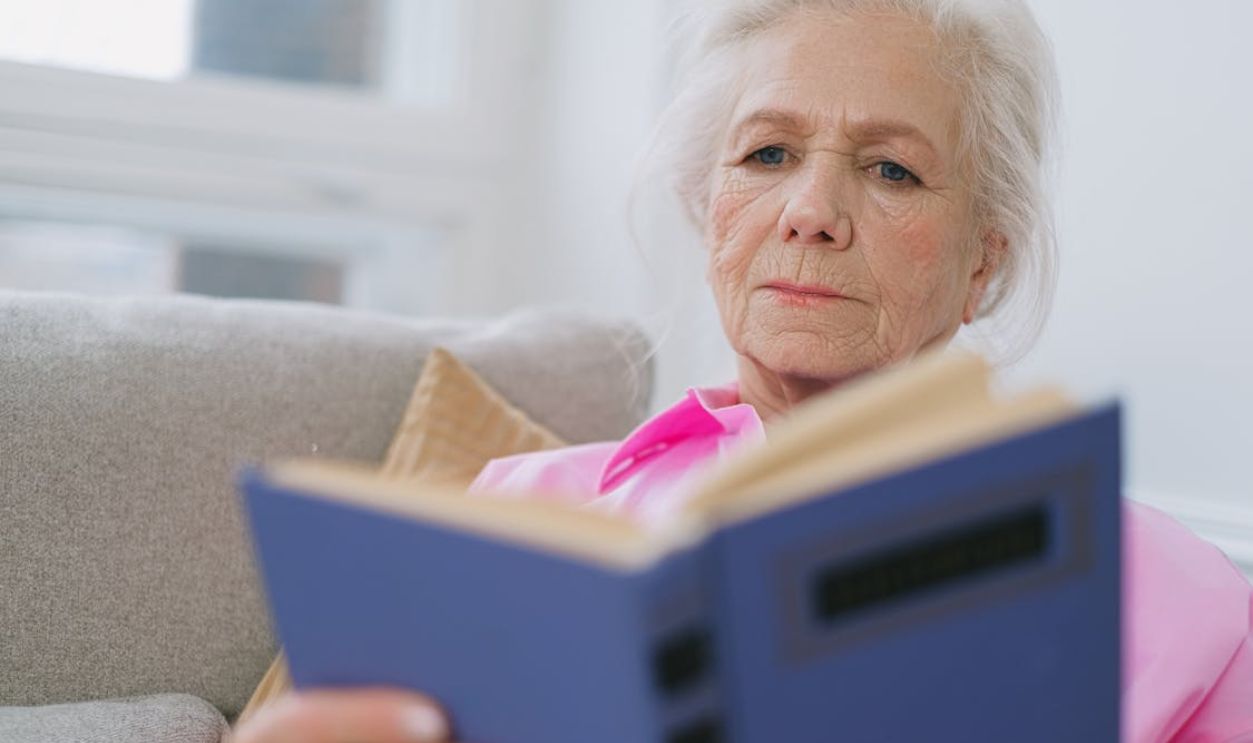 Senior woman enjoying leisure time reading a book indoors in a cozy setting.