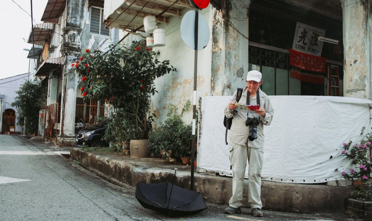 An elderly tourist with a camera and map exploring a historic city street.