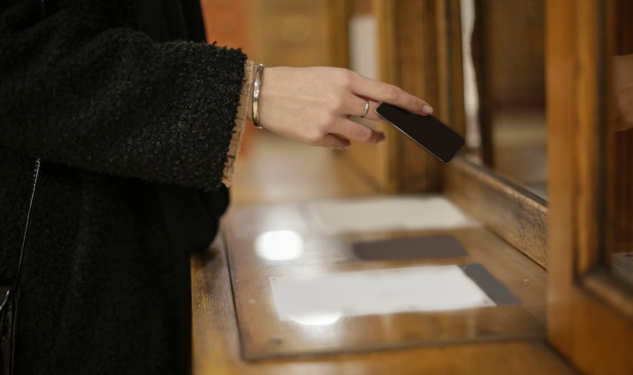 Close-up of a woman's hand using a black card for payment at an indoor counter