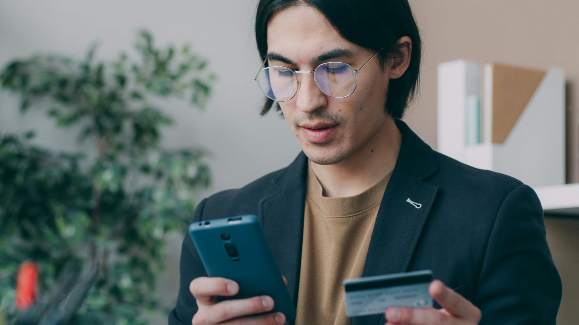 A man holding a smart phone and a credit card