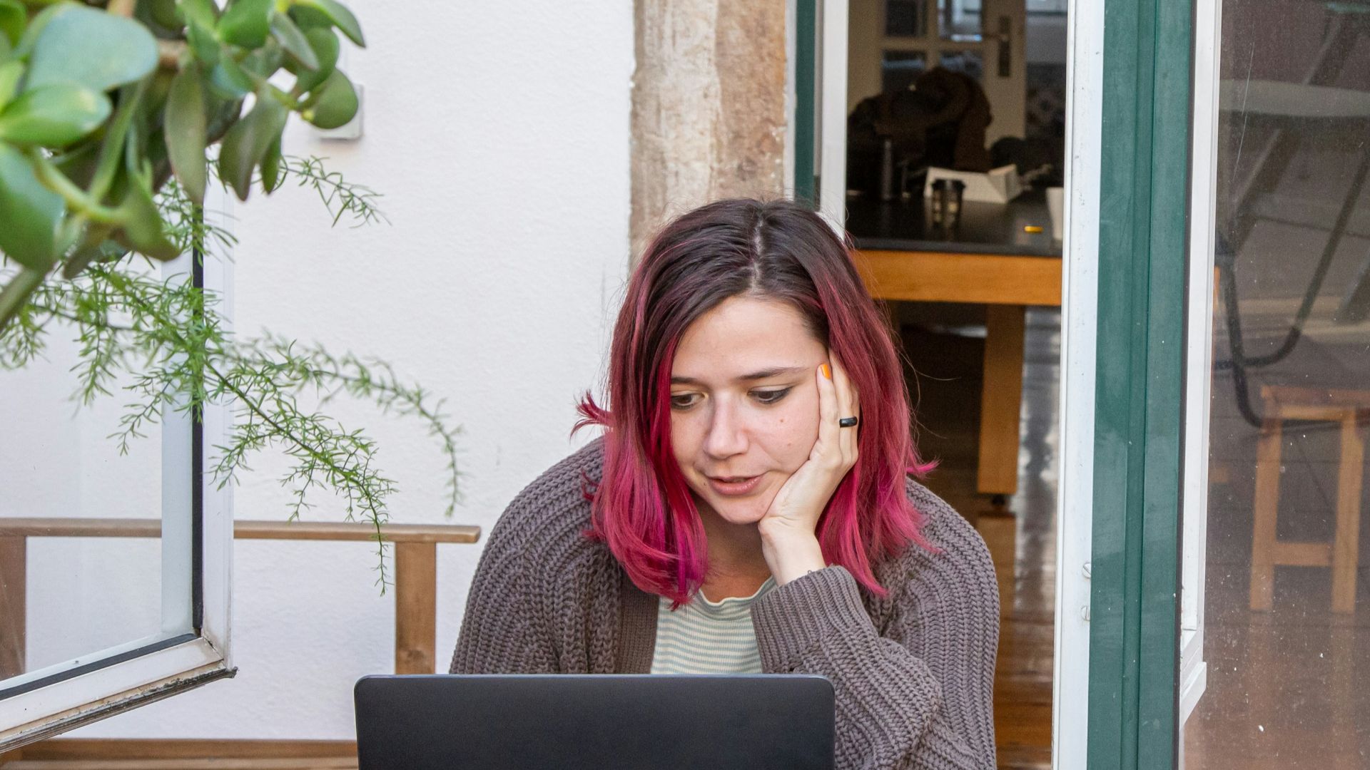 a woman with pink hair is looking at a laptop