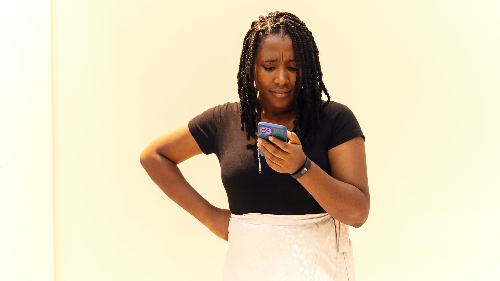 A woman standing in a room looking at her cell phone