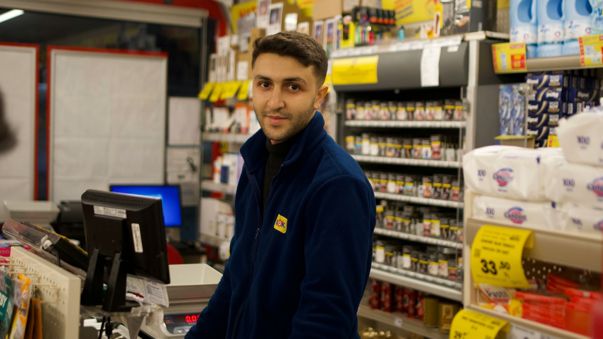 A store clerk smiles while working at the counter.