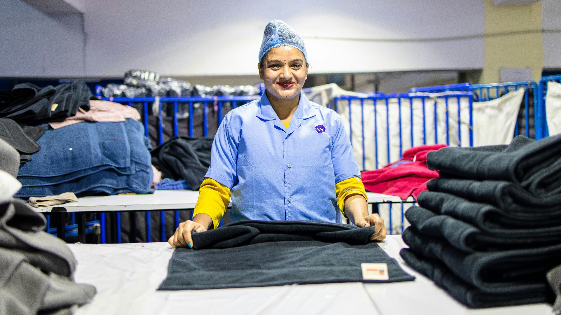 Woman folds clothes in an industrial laundry.