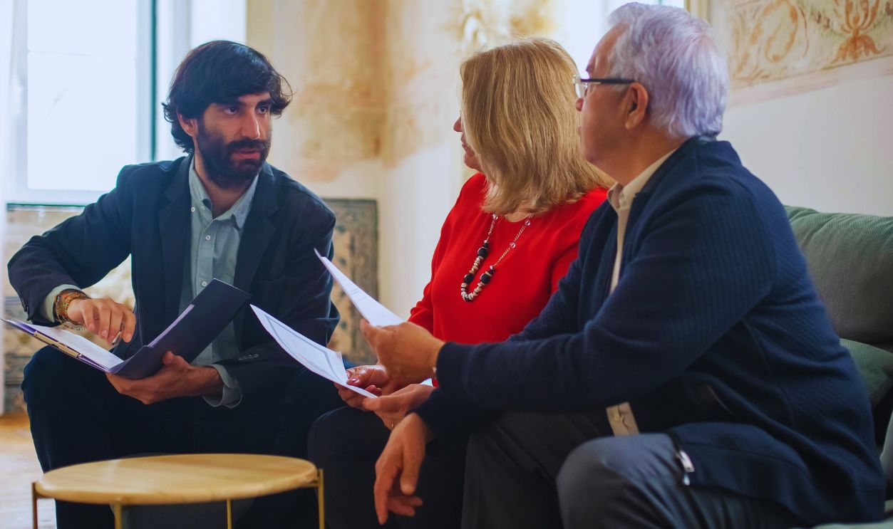 An advisor discussing financial documents with a senior couple indoors in a cozy living room setting