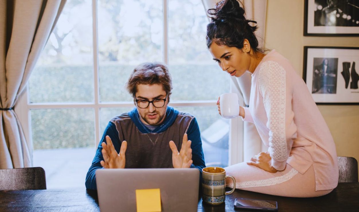 A man and woman working together on a laptop at a wooden table with warm, relaxing ambiance
