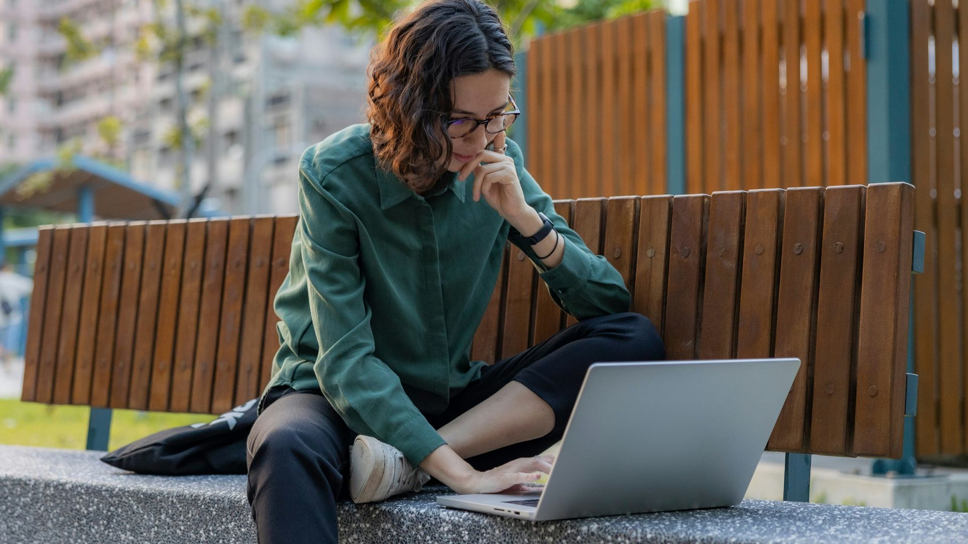 a woman sitting on a bench using a laptop computer