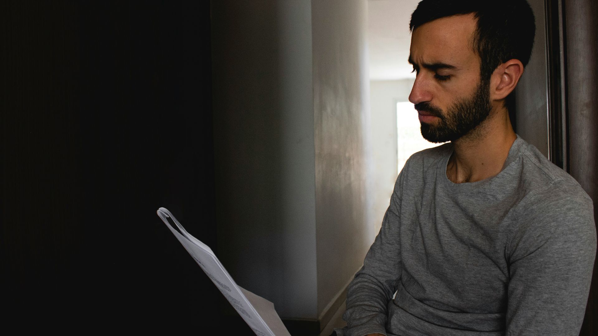 man in gray crew neck shirt holding white printer paper