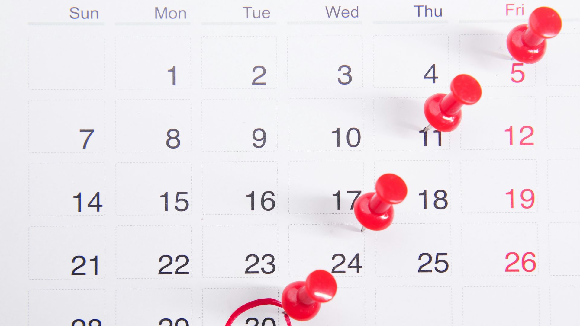a calendar with red push buttons pinned to it