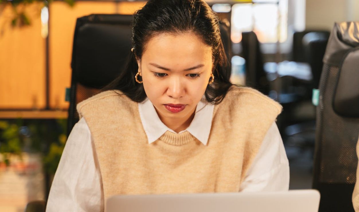 Woman concentrating on laptop in office, showcasing focus and productivity