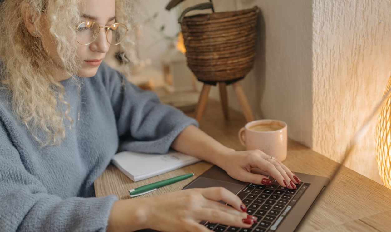 Focused woman with curly hair working on a laptop in a cozy indoor setting