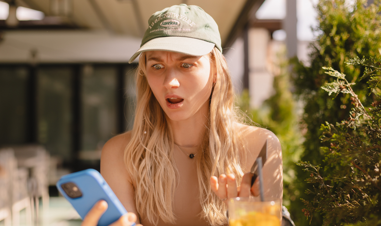 Online payment problem. Shocked frustrated young lady getting bank card declined blocked. Worried confused female overspending too much money from credit card at web shopping via cell sitting in cafe.