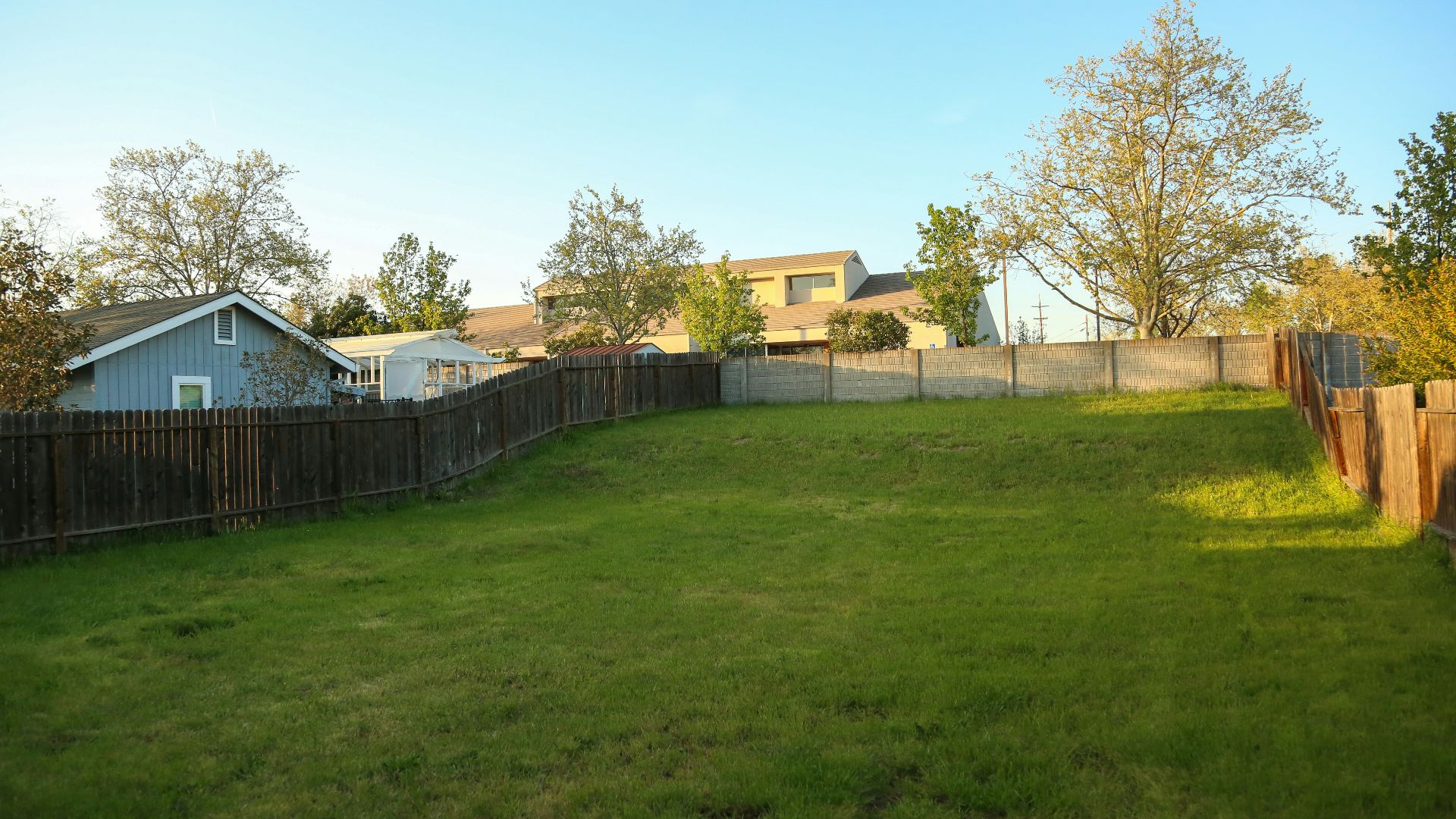 a grassy yard with a fence and a house in the background