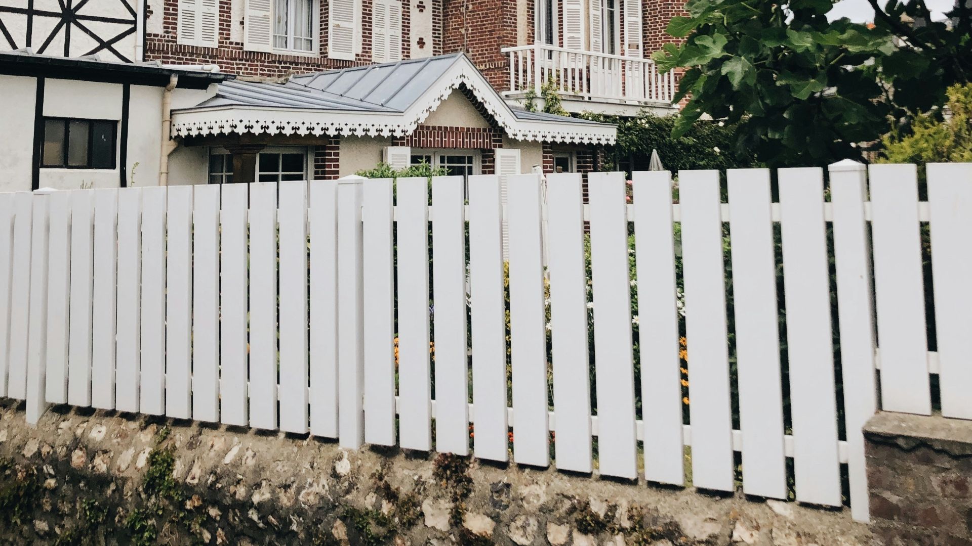 white wooden fence near white and brown house