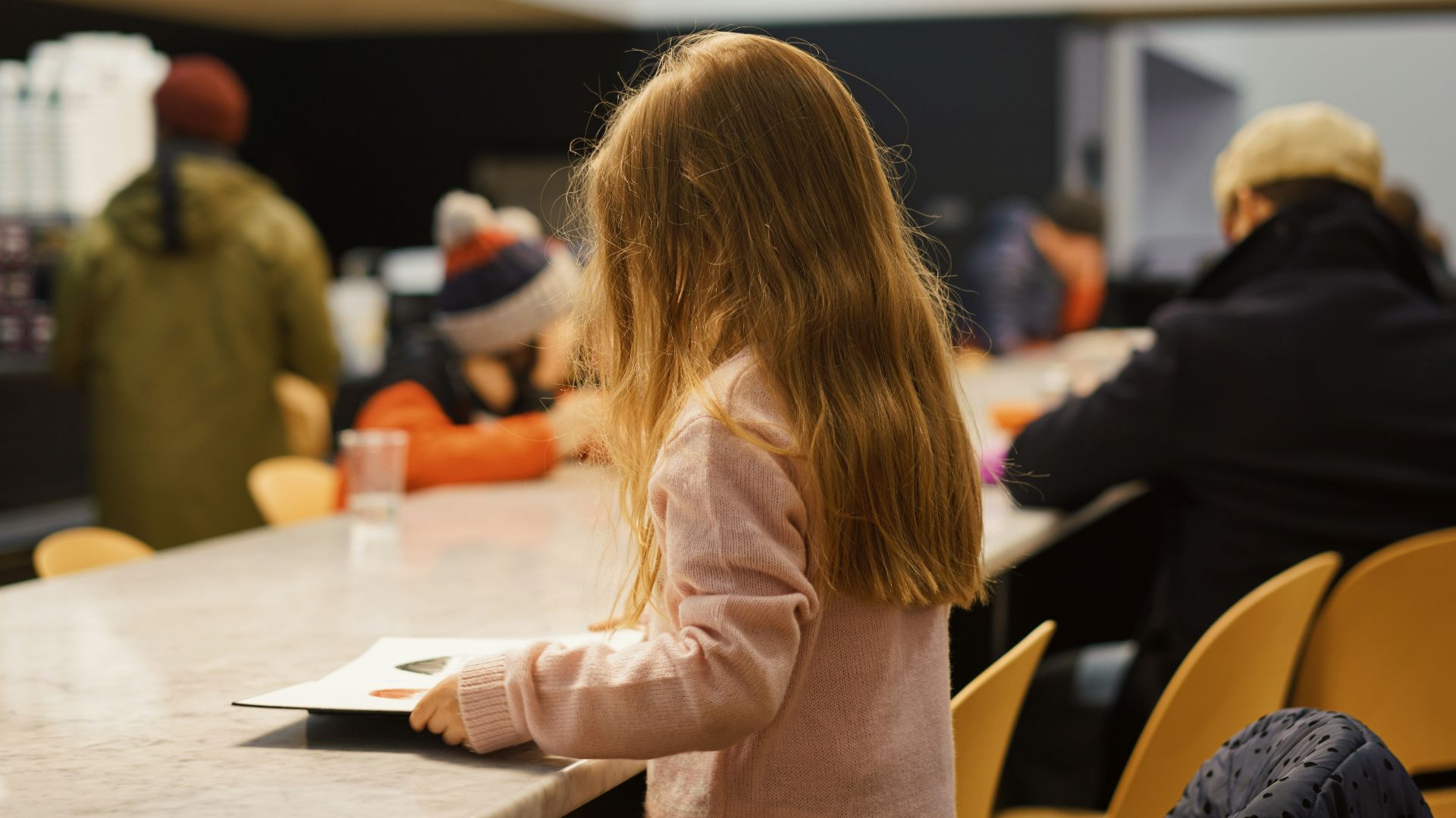 a little girl sitting at a table with a book