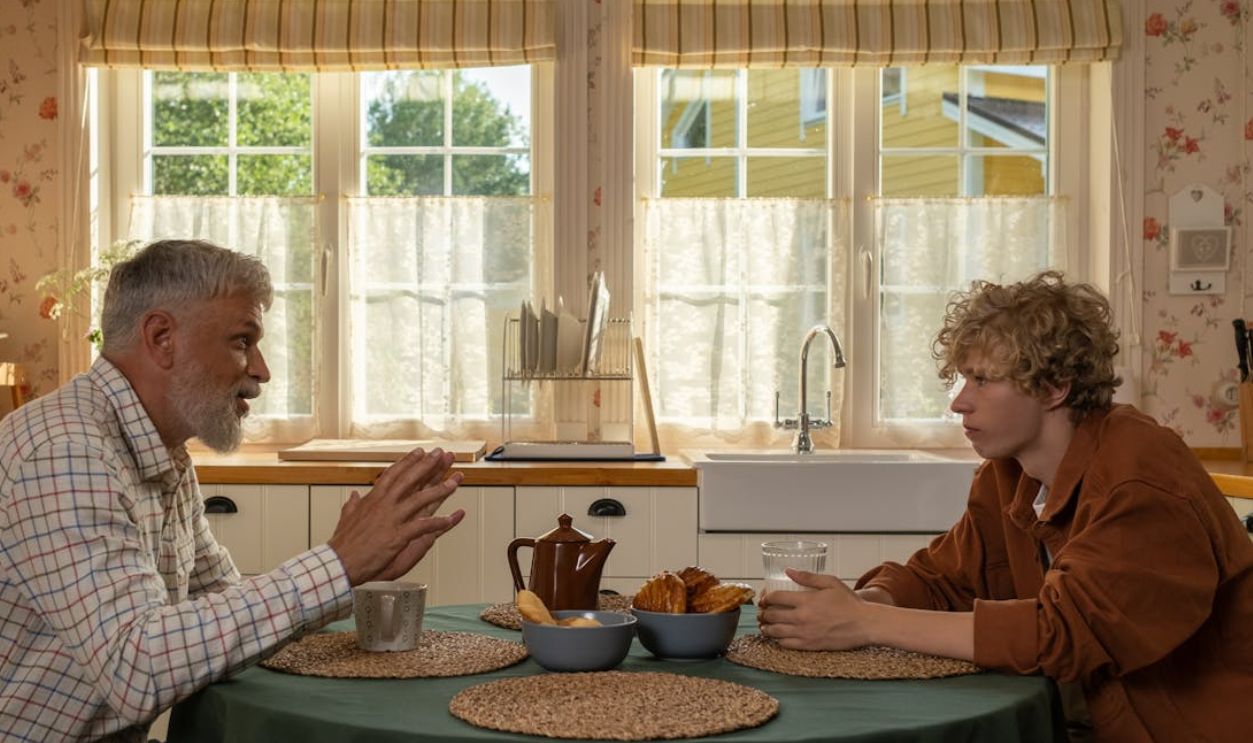 Elderly man and teenage boy enjoying breakfast and conversation at a table