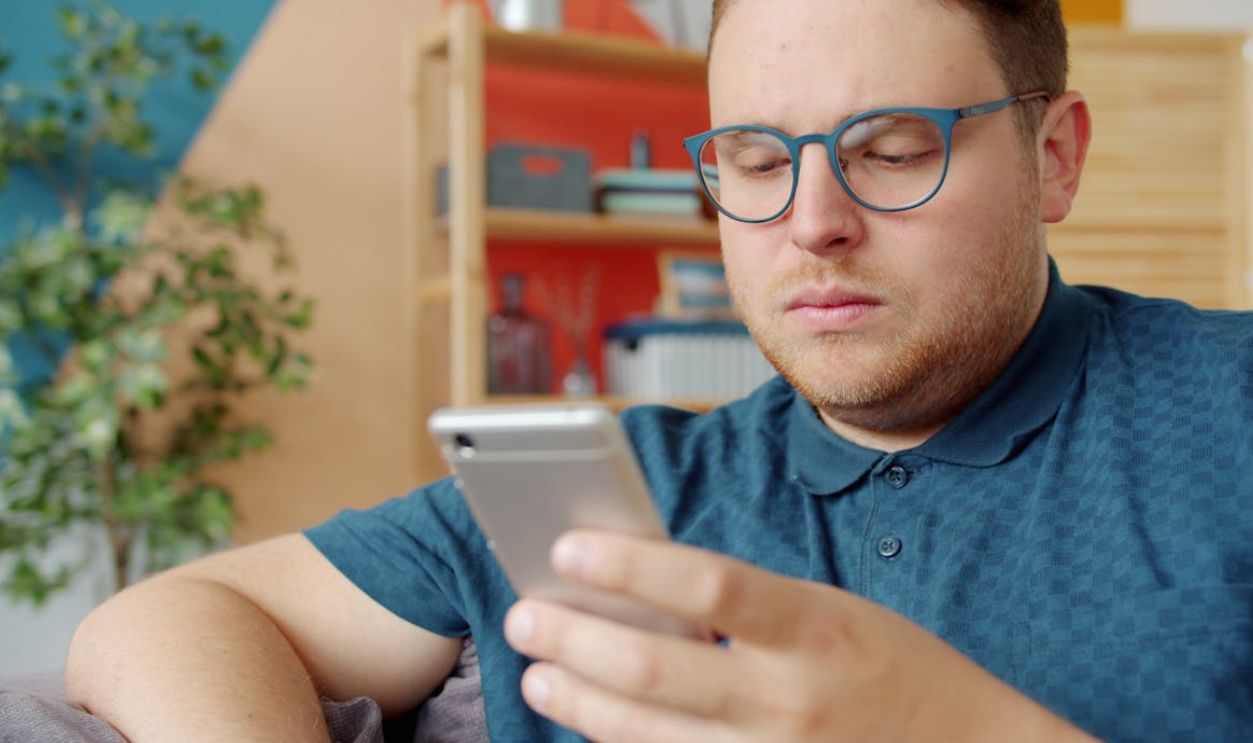 Casual adult man with glasses using smartphone at home