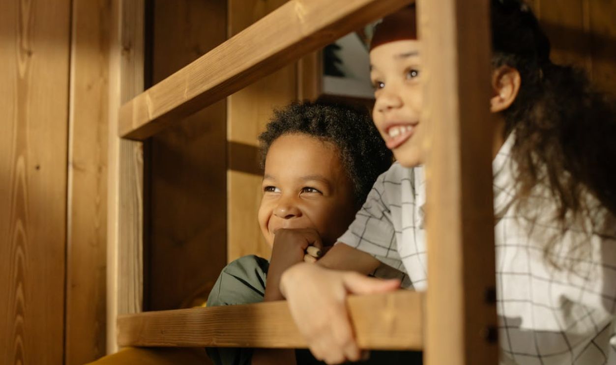 Happy children enjoying a playful moment indoors, surrounded by wooden beams and warm lighting.