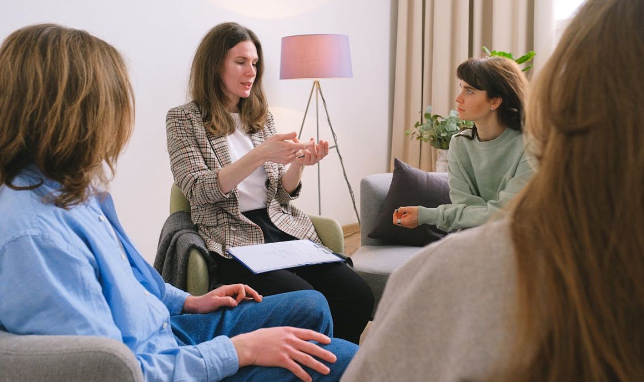 A group therapy session with women discussing and sharing experiences indoors.