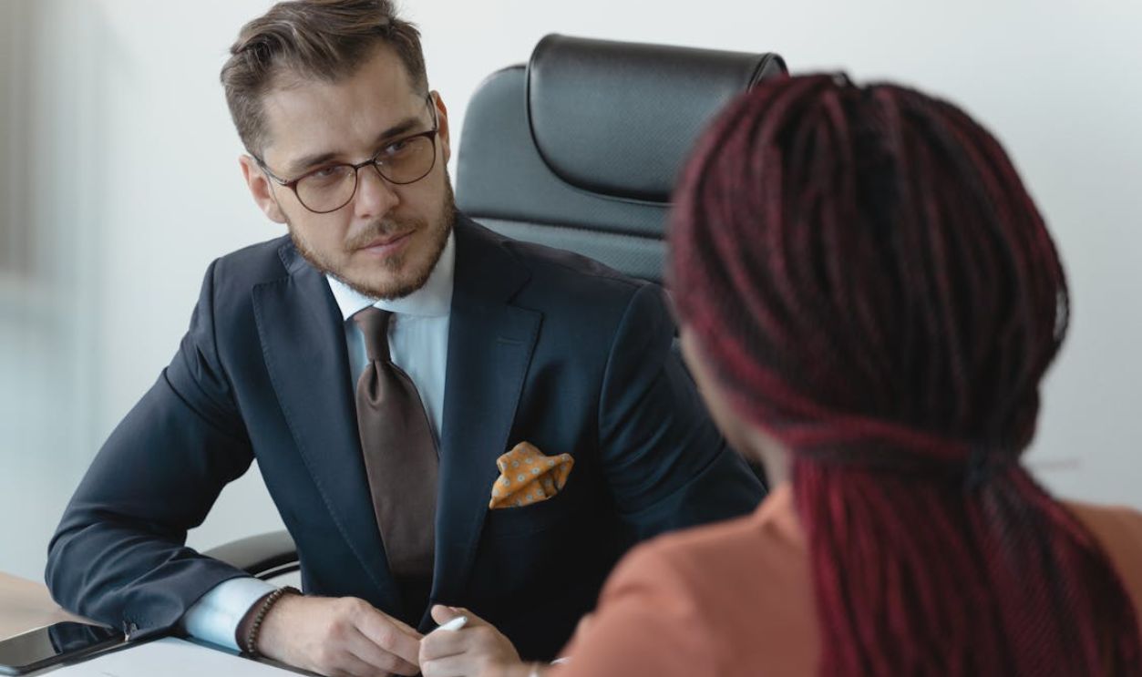 Two professionals engage in a serious discussion at a corporate meeting.
