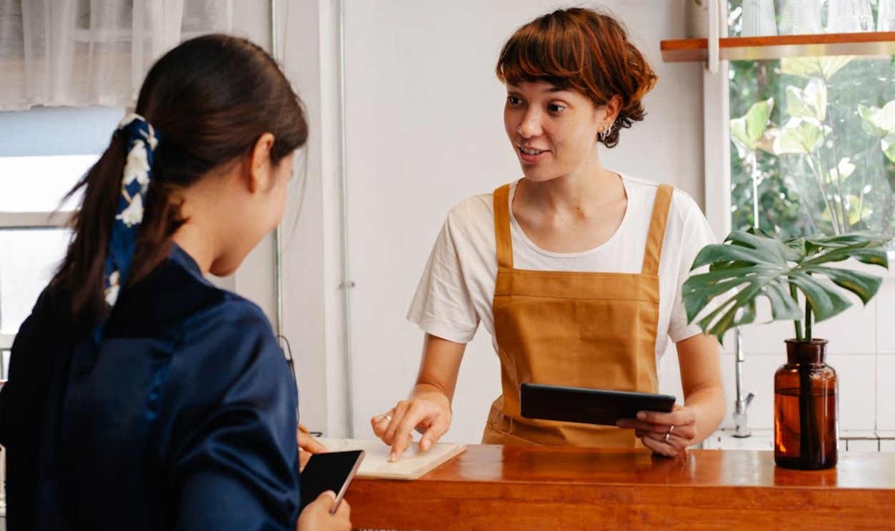 A barista helping a customer with a tablet in a modern cafe setting. Natural interaction.