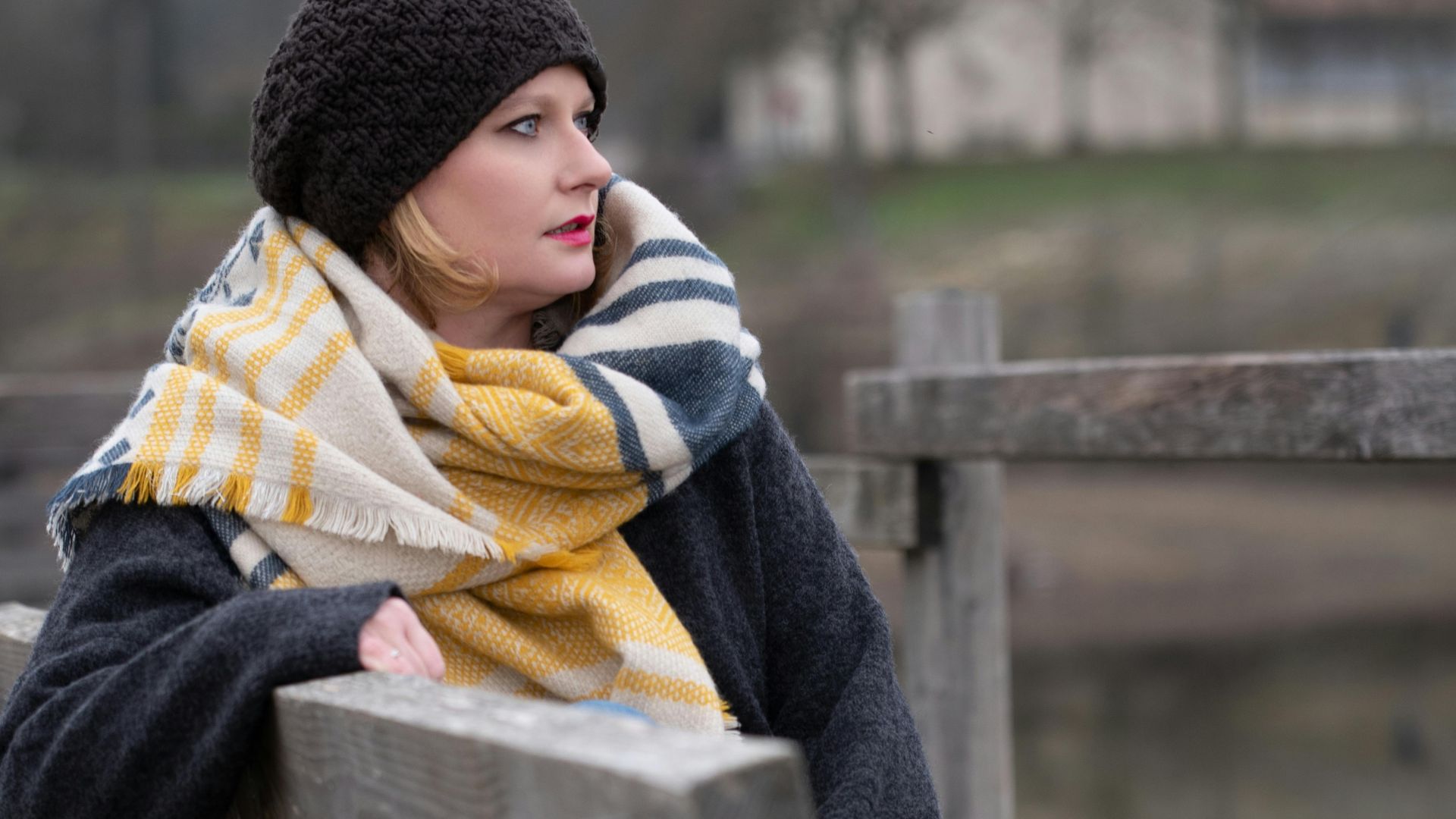 Stylish woman in warm winter attire enjoys a peaceful moment on a bench in Lyon, France.