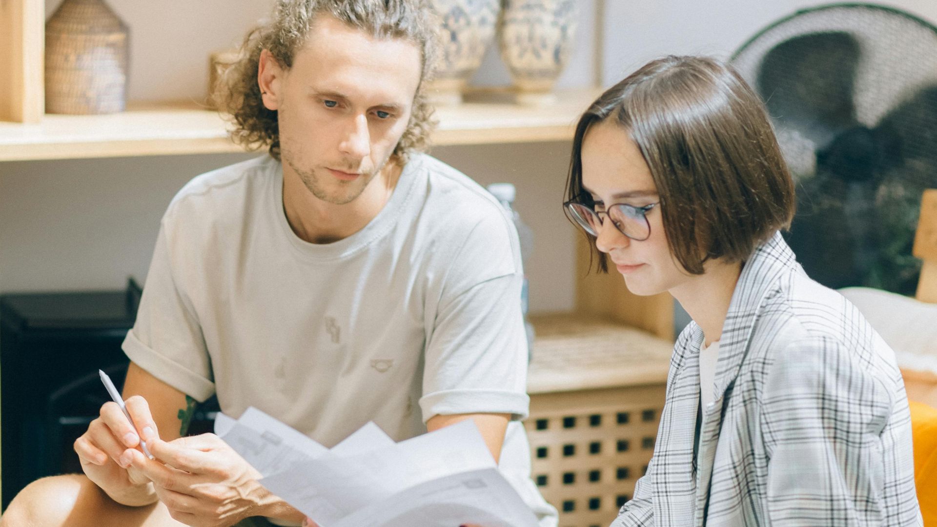 A man and woman discussing documents in a cozy workspace setting.