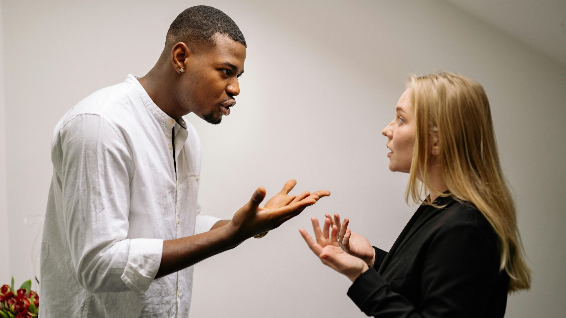 A man and woman engaged in a heated office argument, displaying emotion and intensity.